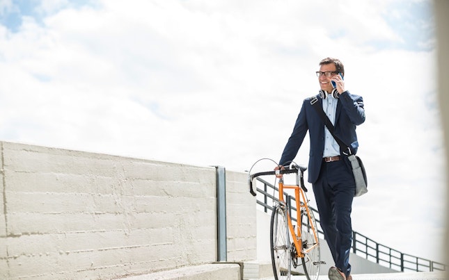 Businessman Pushing his Bike While Talking on the Phone