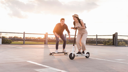 Woman and Man Riding a Skateboard and an Electric Scooter